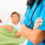 Nurse with folded arms looking over old person